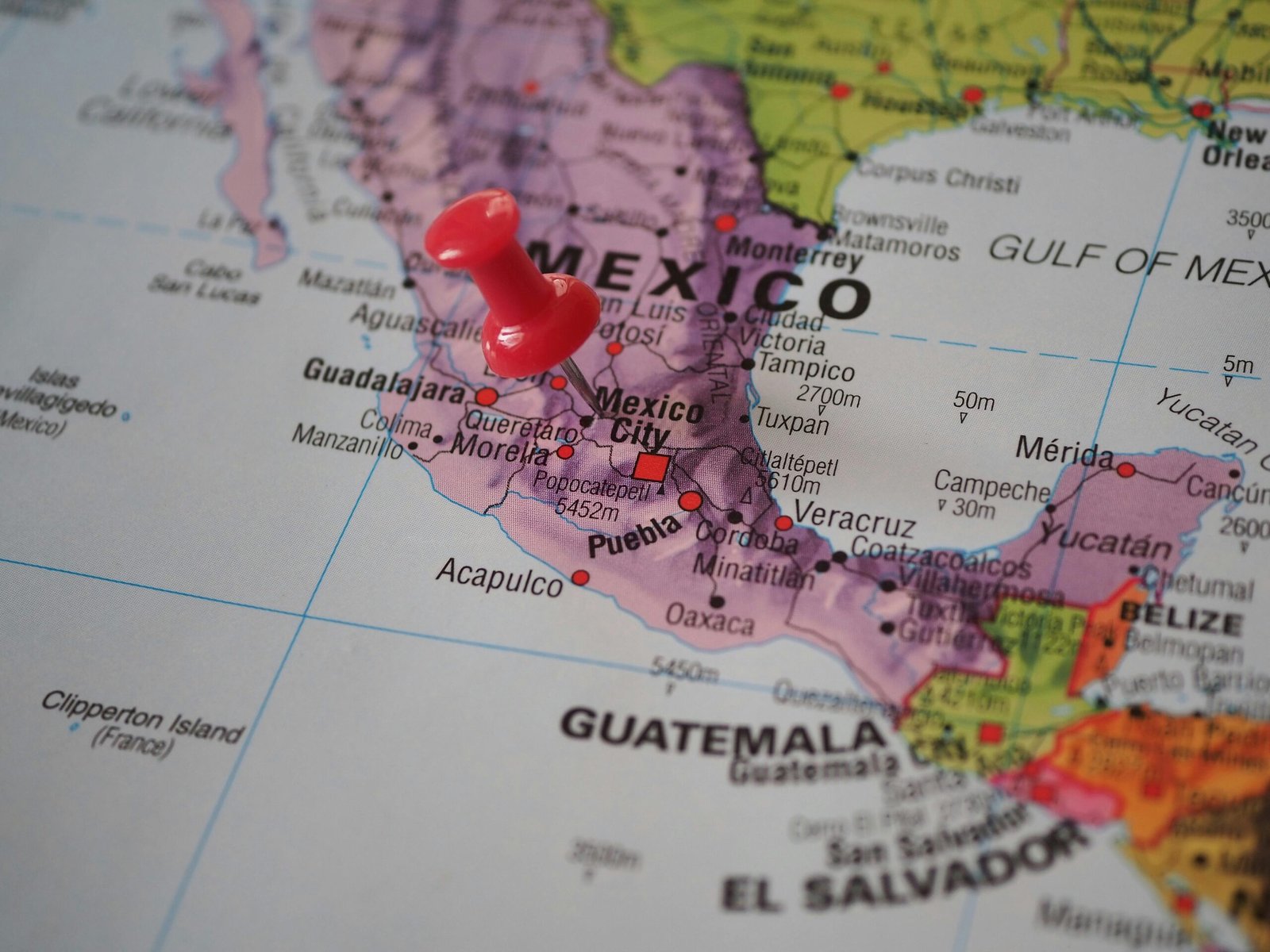 pexels-photo-19937220-19937220 Detailed close-up of a map featuring Mexico with a red pushpin highlighting a location.